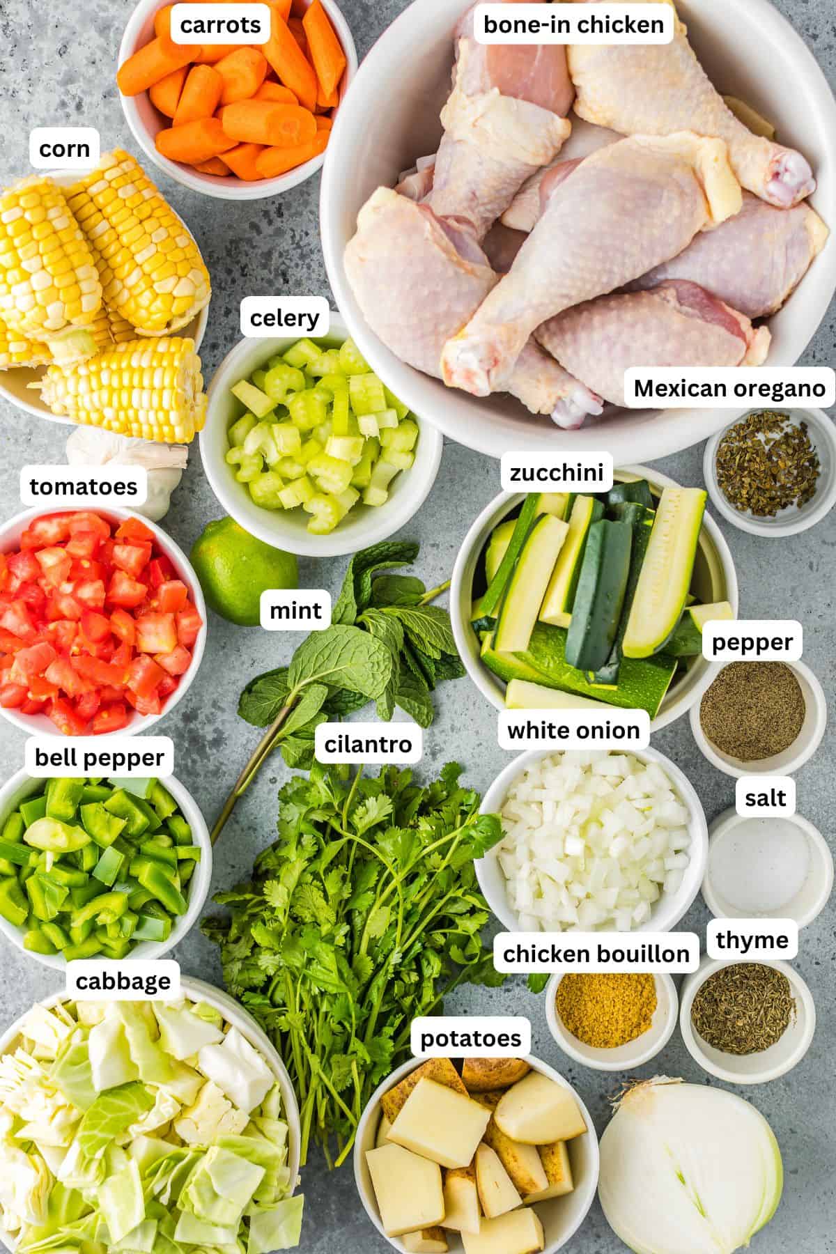 Ingredients for caldo de pollo recipe in order from top to bottom: carrots, corn, celery, chicken, tomatoes, zucchini, Mexican oregano, bell pepper, mint, cilantro, white onion, pepper, salt, cabbage, potatoes, chicken bouillon, thyme.