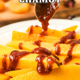 Chamoy on a spoon being drizzled over sliced mangos.