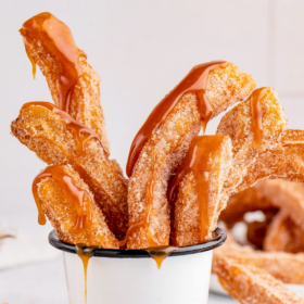 Churros in a cup drizzled with caramel sauce.