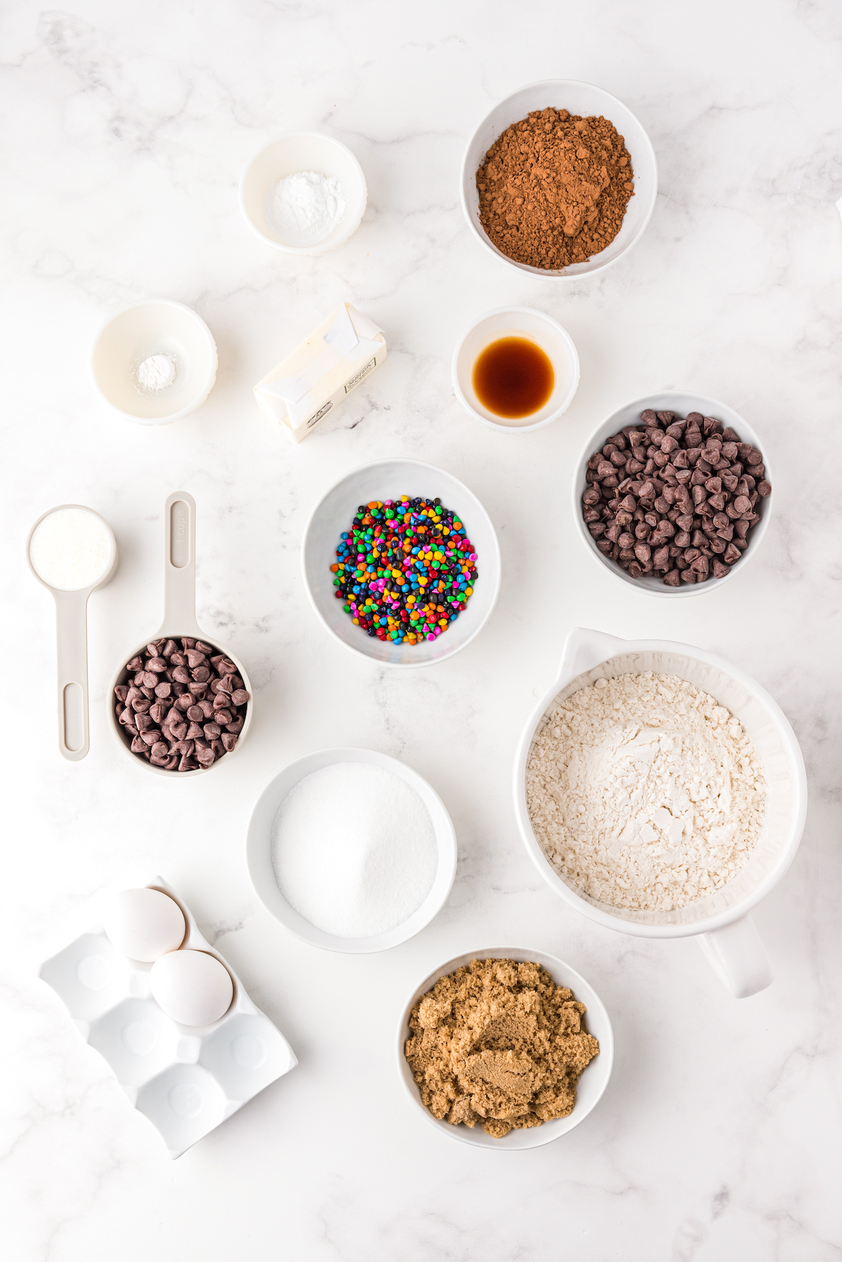 The ingredients for a cosmic brownie crumbl cookie recipe, measured into small dishes.