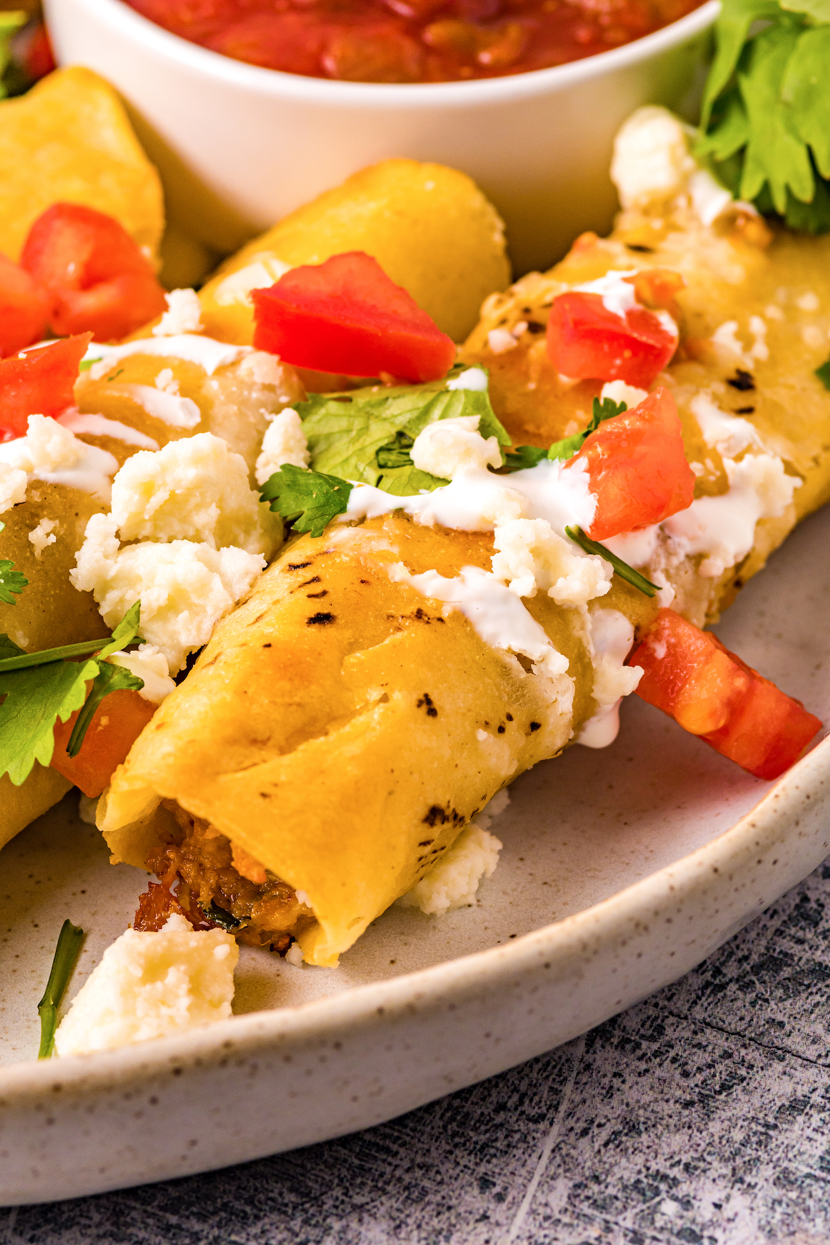 Close-up of homemade taquitos with toppings.