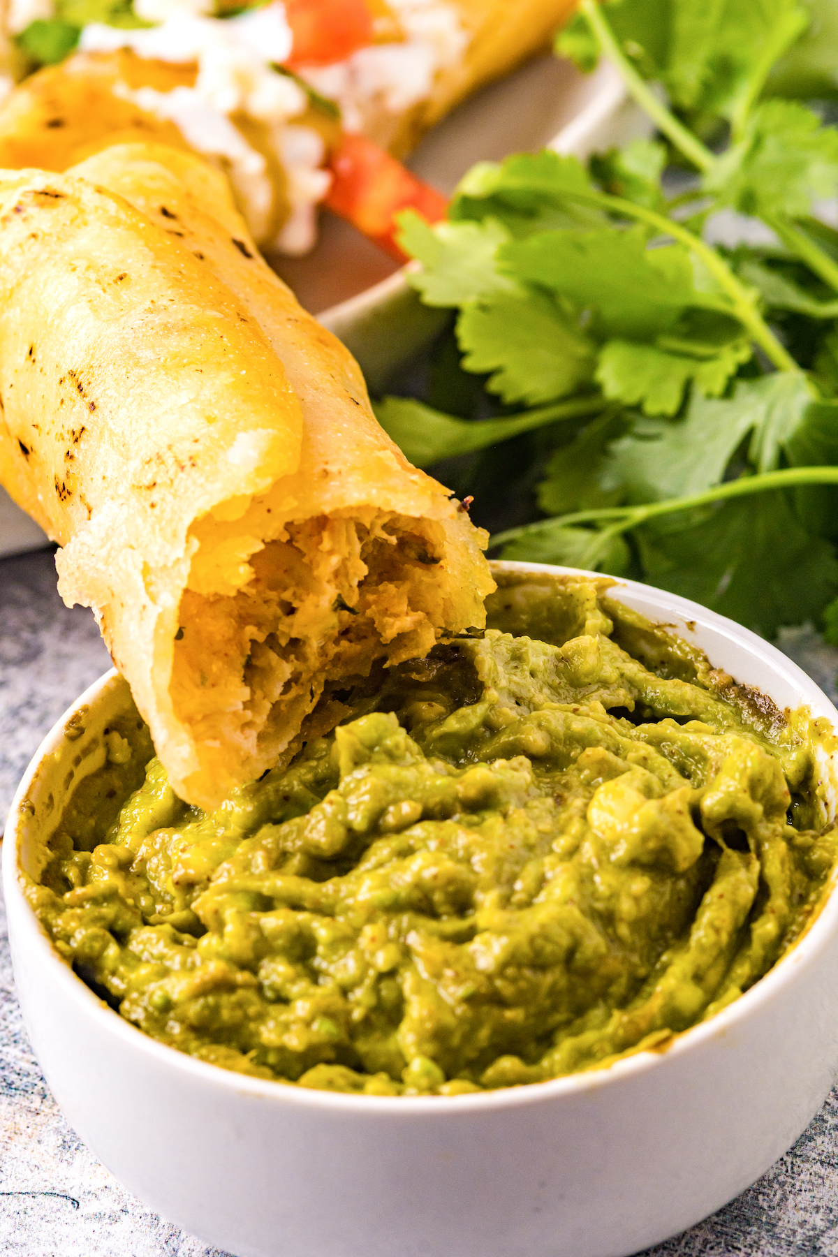 Dipping homemade taquitos into guacamole.