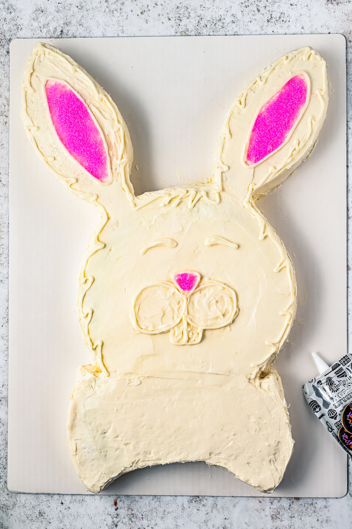 A bunny-shaped cake with pink sugar to make the inner ears, and white icing to outline the eyes, nose, and teeth.