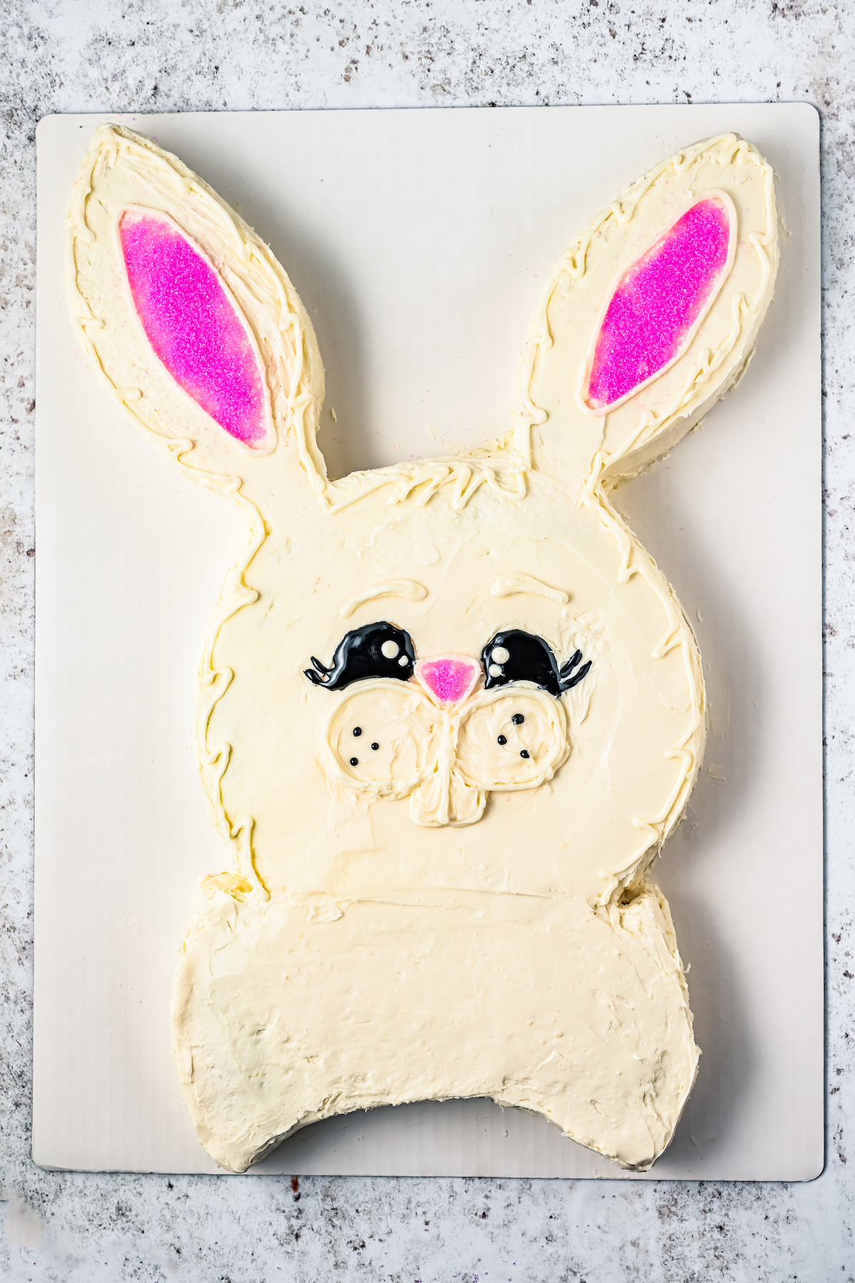 A bunny cake with ears, eyes, nose, teeth, and whiskers.