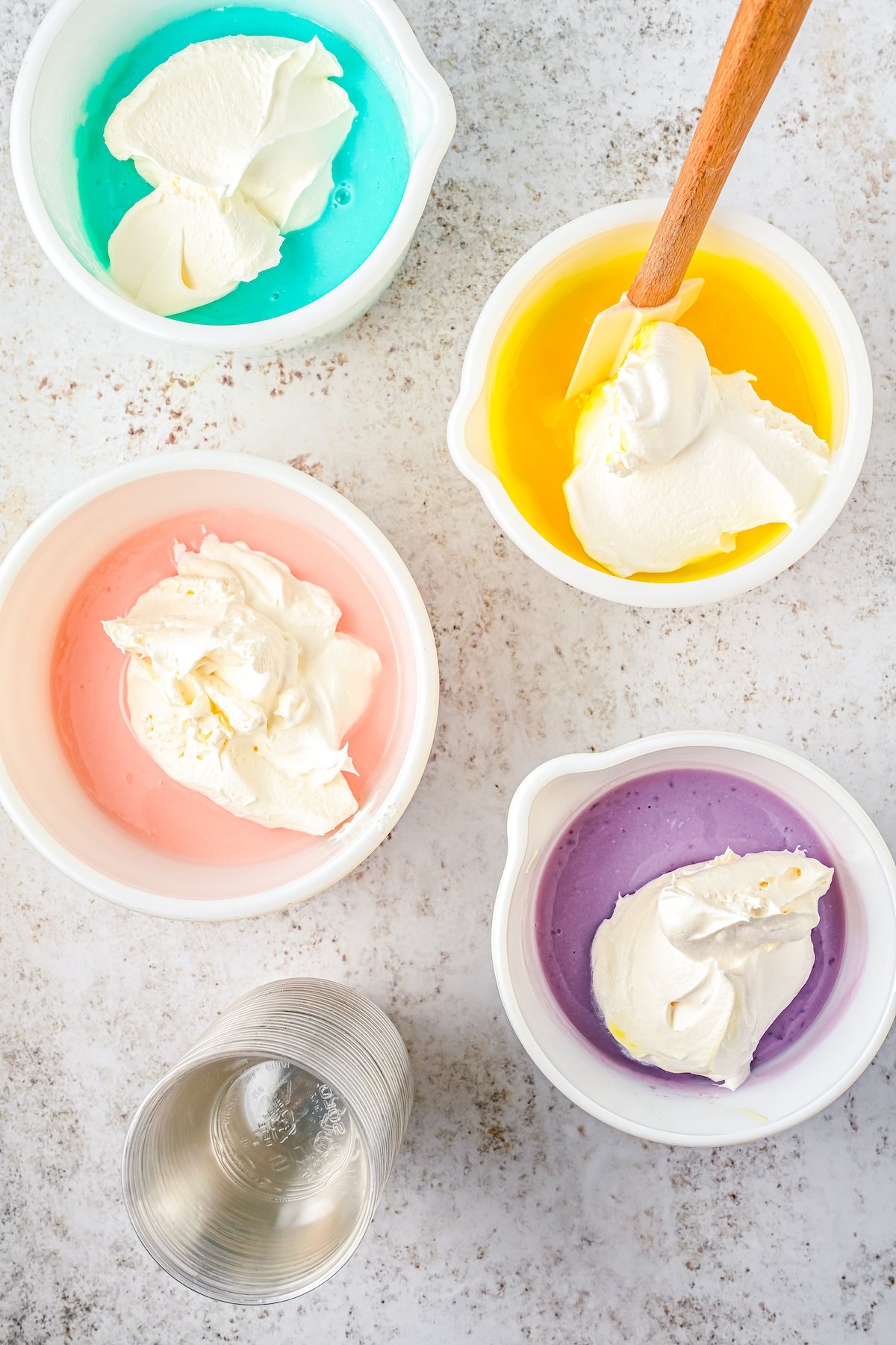 Stirring whipped cream into different colored bowls of Jello.