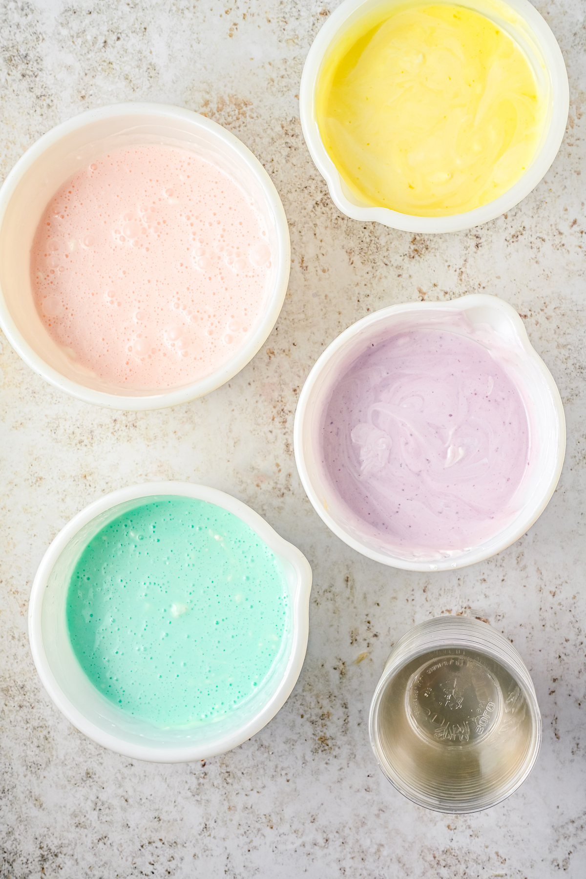 Creamy pastel Jello mixtures in separate mixing bowls.