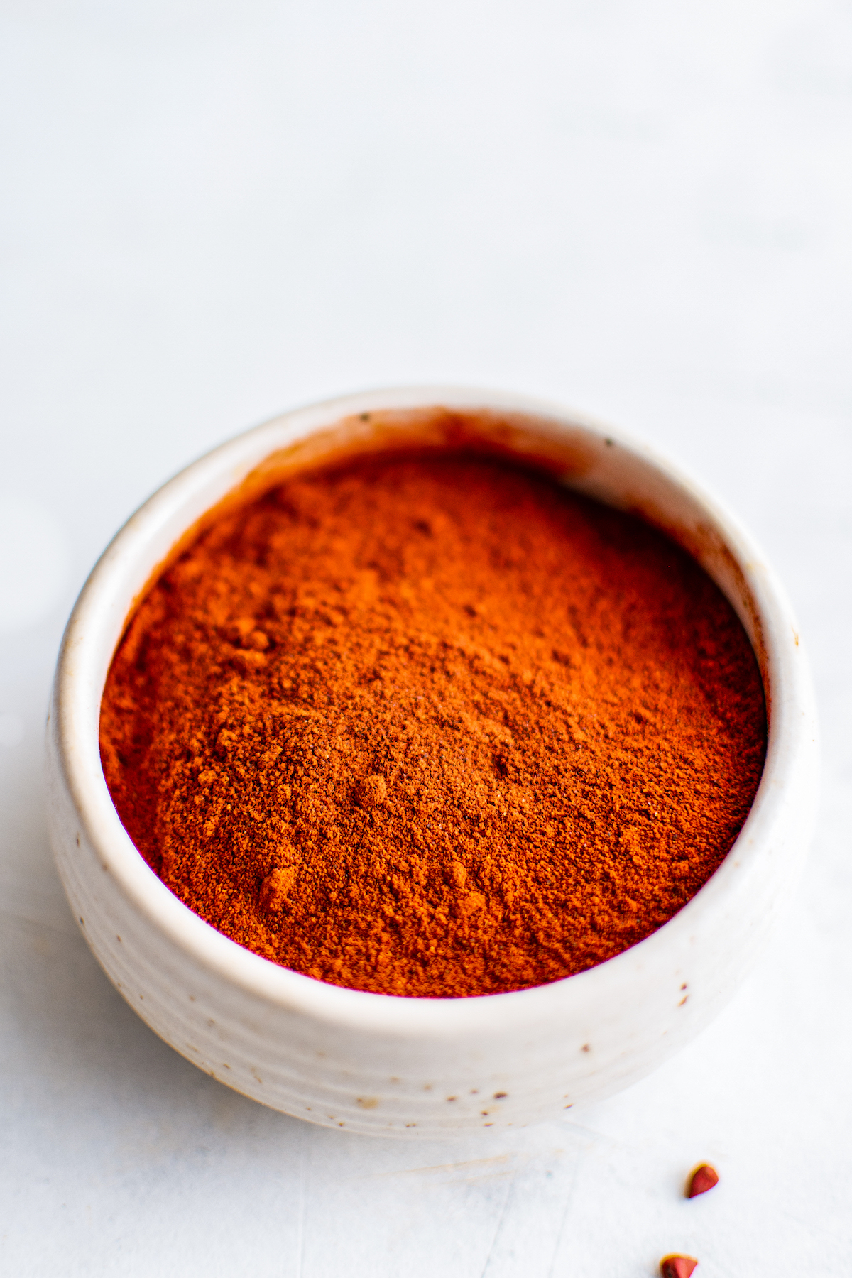 A bowl filled with crushed annatto seeds.