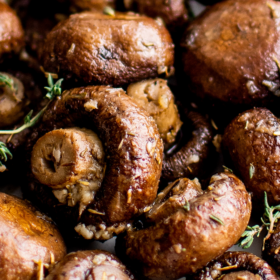 Roasted mushrooms with herbs and garlic on a white platter.
