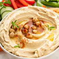 A bowl of hummus with an assortment of fresh vegetables.