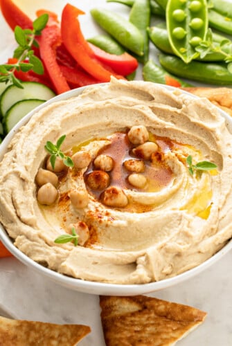 A bowl of hummus with an assortment of fresh vegetables.