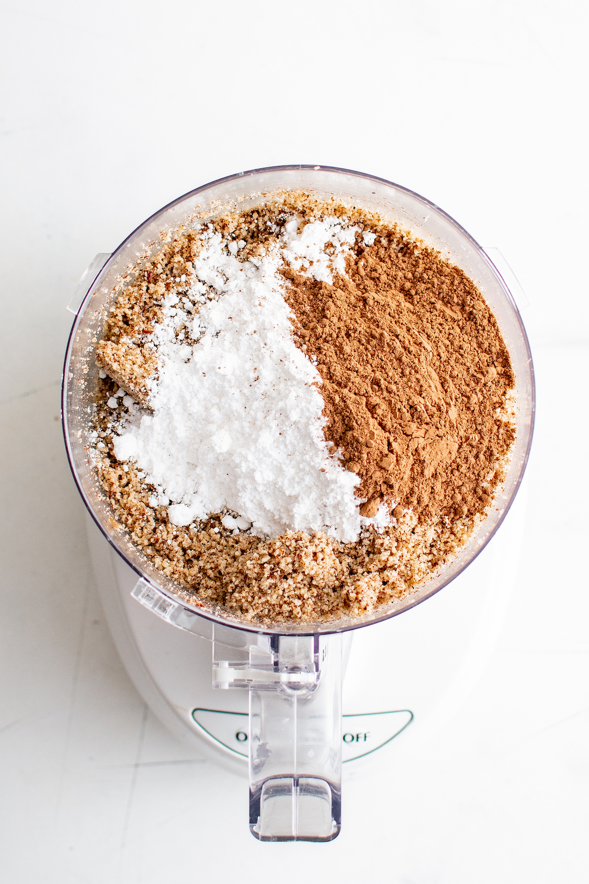 Ground hazelnuts, powdered sugar, and other ingredients in a food processor.