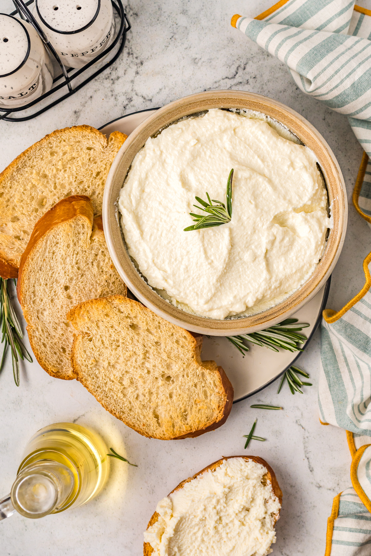Homemade ricotta in a bowl with toasted baguettes on the side.