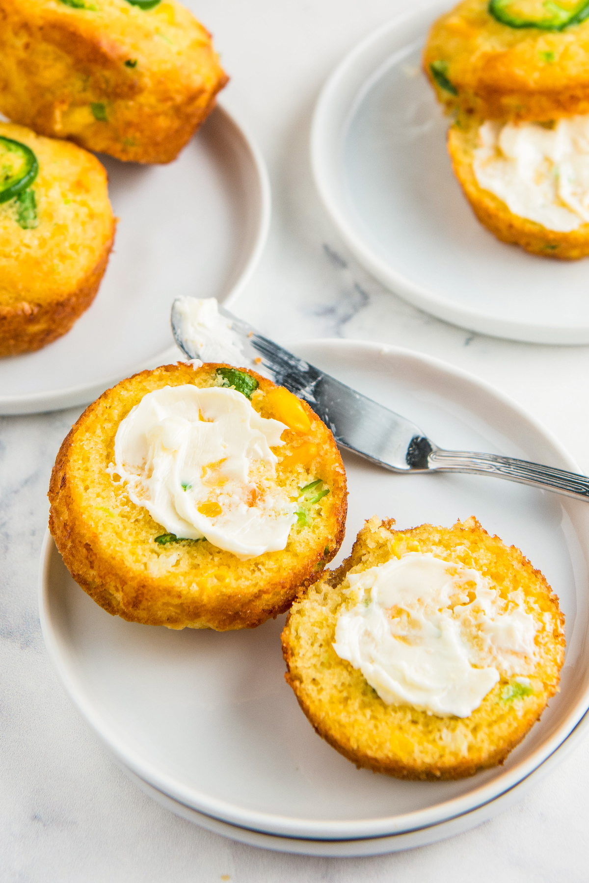 A corn muffin split and spread with butter on a small dessert plate.