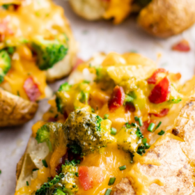 Loaded baked potatoe with broccoli, bacon and cheese on parchment paper.