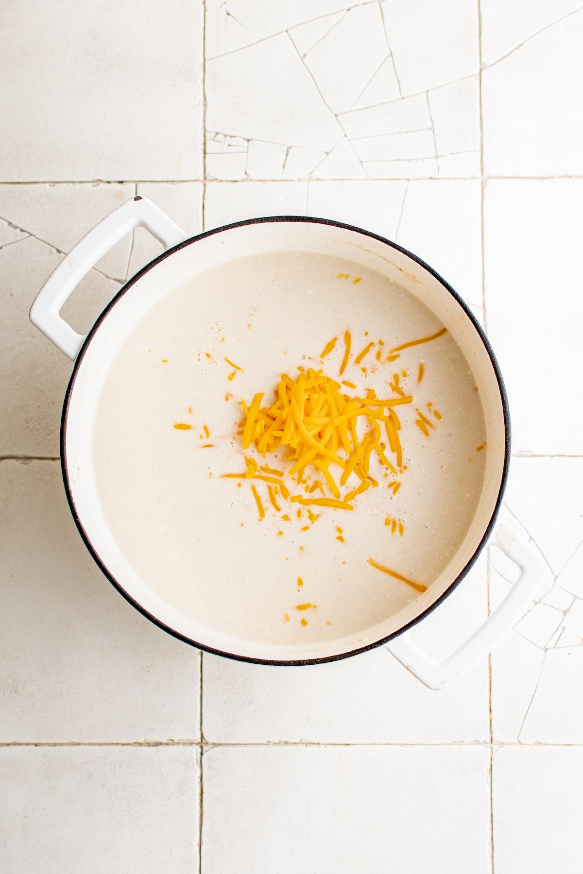 Shredded cheese added to a soup pot.