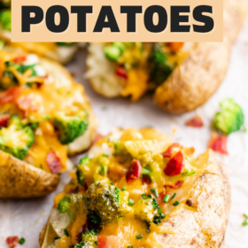 Baked potatoes loaded with cheese, broccoli and bacon on parchment paper.