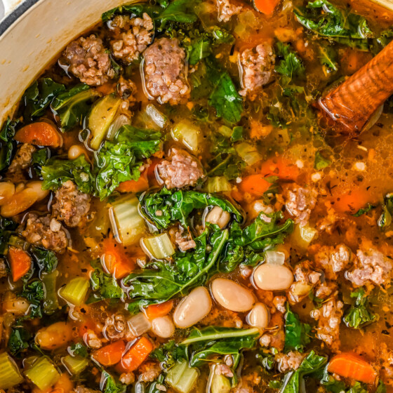 A pot of soup with kale, sausage, and white beans.