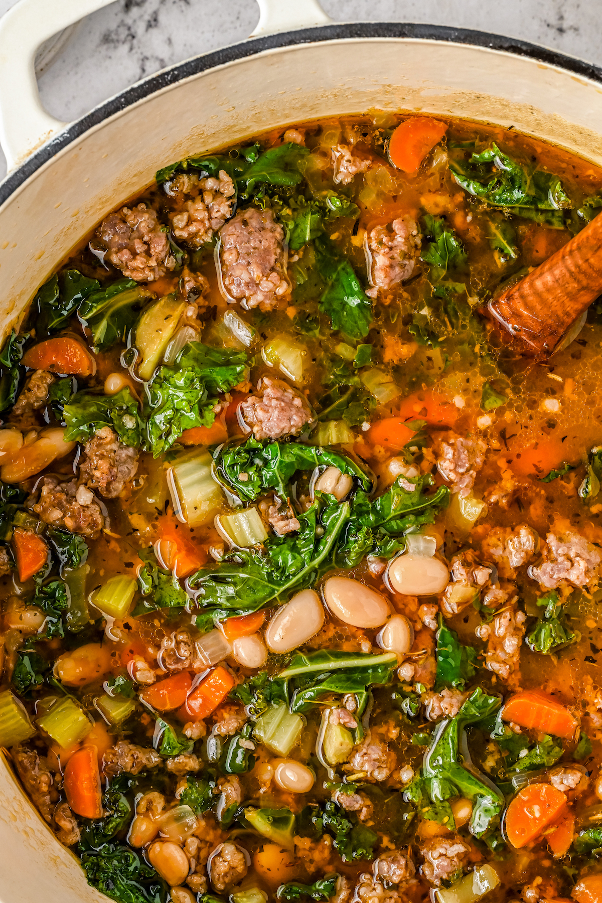 A pot of soup with kale, sausage, and white beans.
