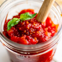 Homemade tomato jam in a jar with a wooden spoon.
