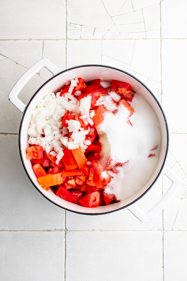 Diced tomatoes, sugar, onion, and other ingredients in a pot.