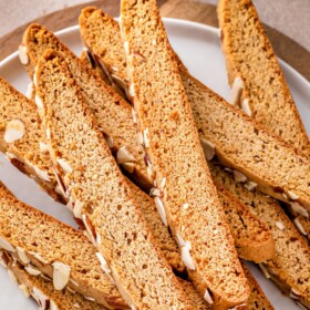 Almond biscotti stacked on a white plate.