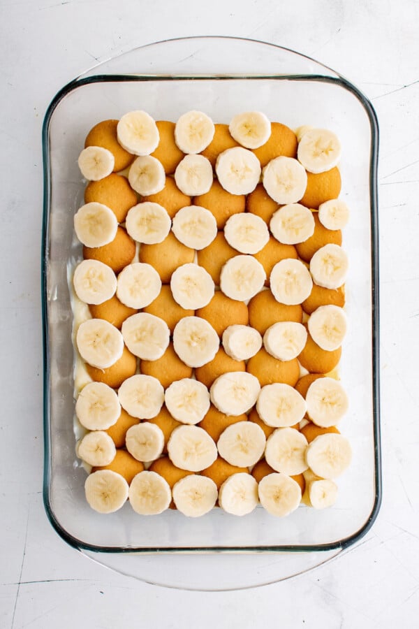 Layering the dessert with wafers and sliced bananas.