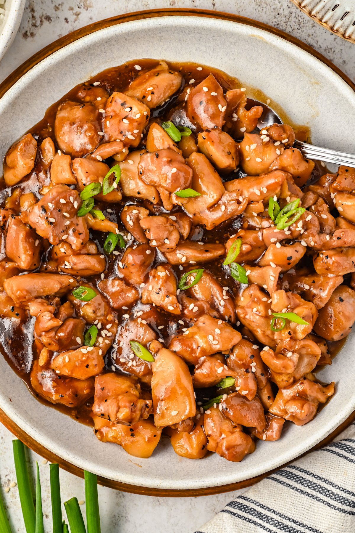 Bourbon chicken with green onions and sesame in a plate.