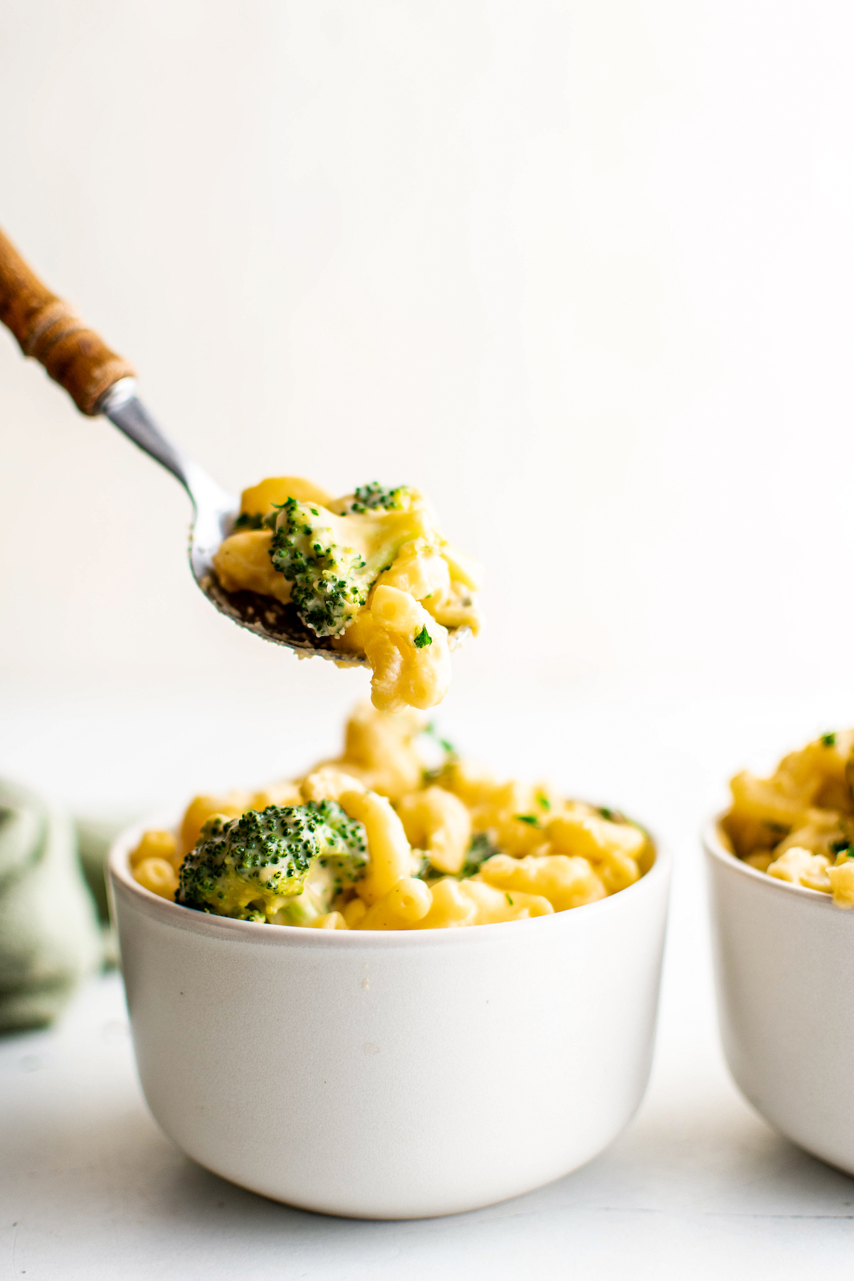 Lifting a bite of broccoli mac and cheese out of a bowl.