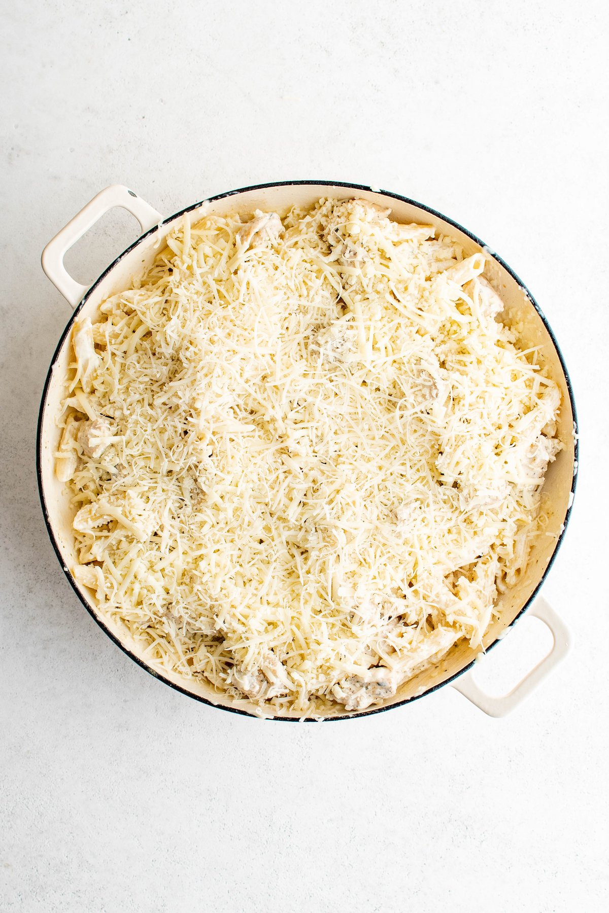 Sprinkling parmesan over the pasta.