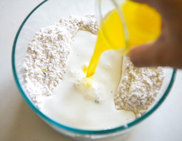 Butter being poured into a bowl of flour, milk, baking powder and more.