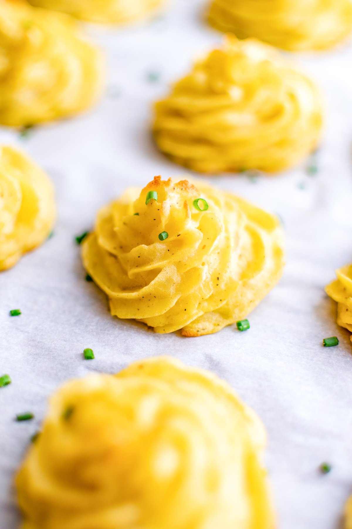 Rows of duchess potatoes on a baking sheet.