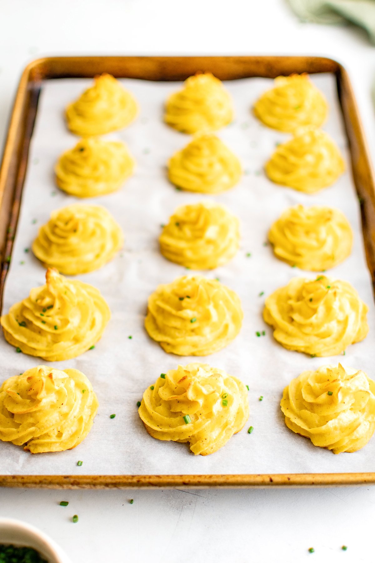 A baking sheet of piped baked potato swirls.