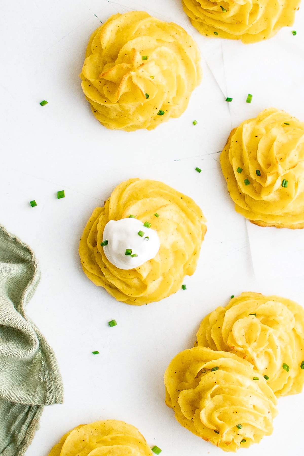 Overhead shot of pomes de terre duchesse topped with chives and sour cream.