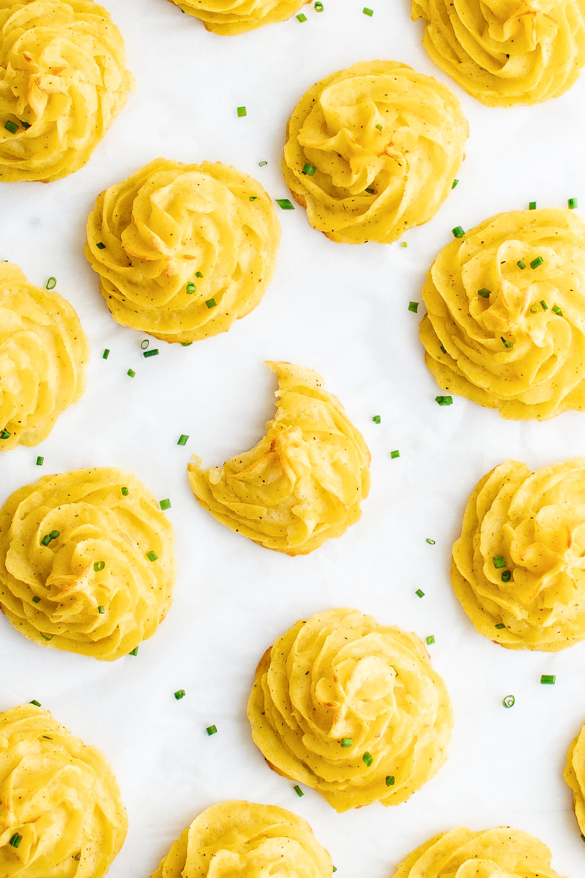 Potato swirls on a baking sheet. One has had a bite taken from it.