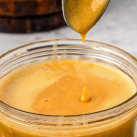 A spoon in a bowl of dulce de leche on a plate.