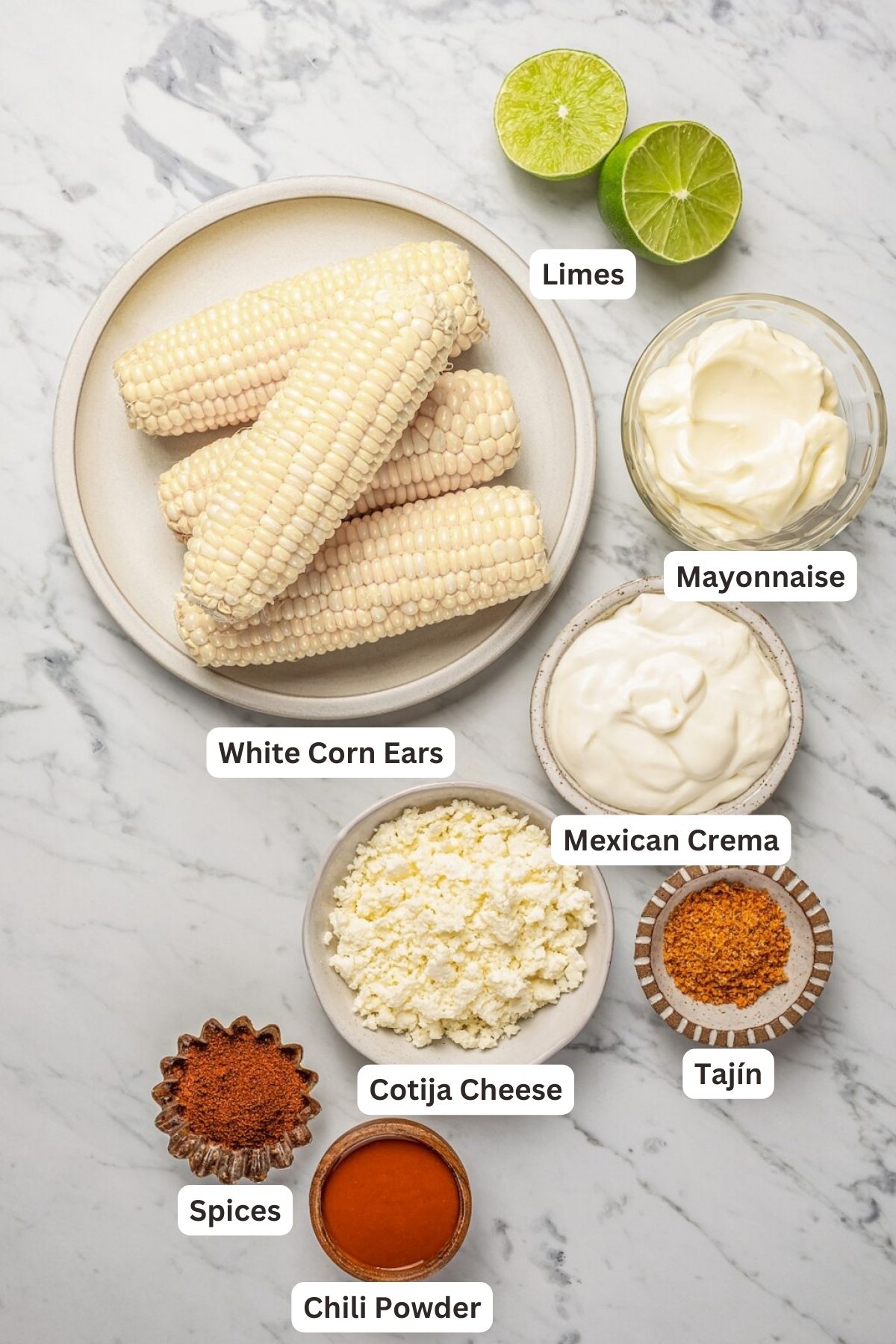 Ingredients for Elote in bowls on a marble counter top.