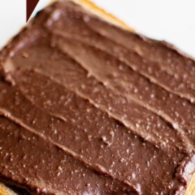 Nutella spread on a slice of toast with a bite taken out of it.