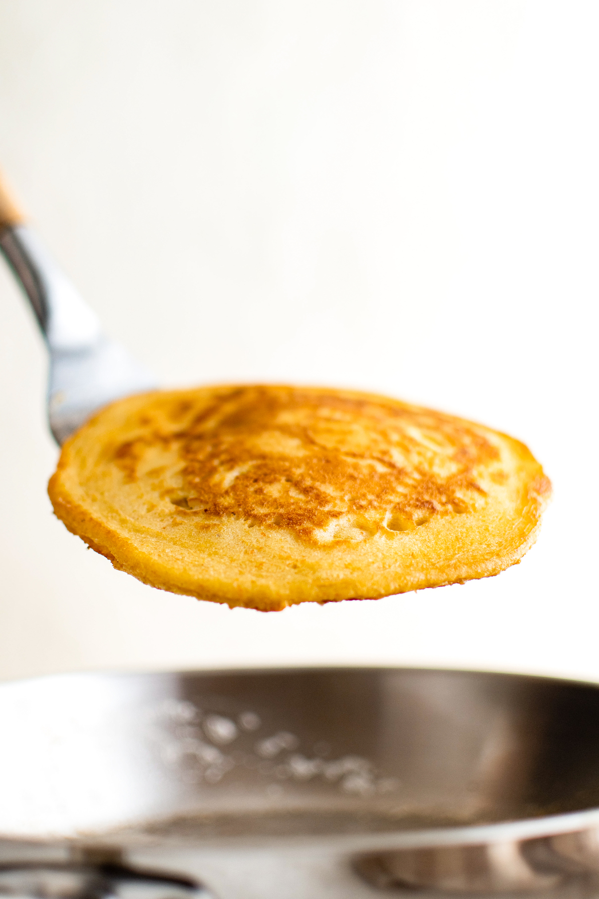 Lifting a cornmeal pancake from a skillet.