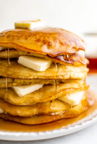 A stack of johnny cakes drenched in syrup.