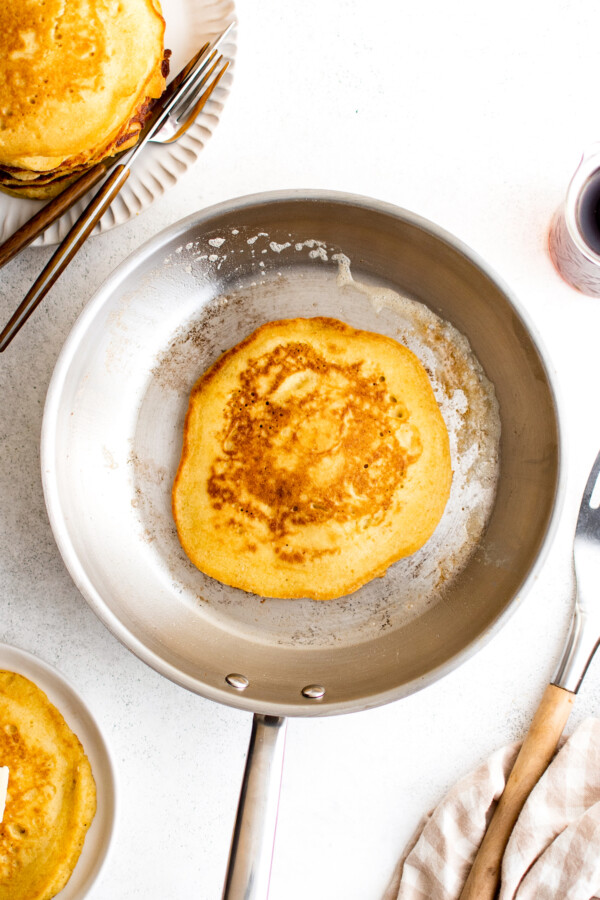 A skillet with a golden-brown hoe cake in it.