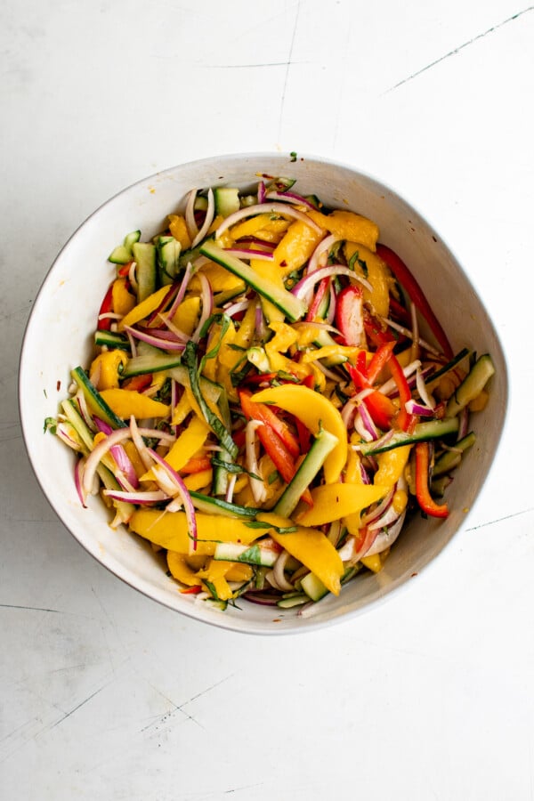 Mixed veggies and mango in a salad bowl.