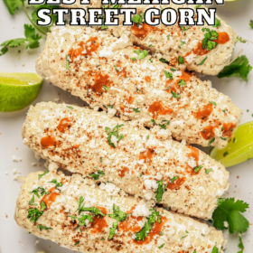 Mexican street corn on a platter with cilantro and lime wedges.