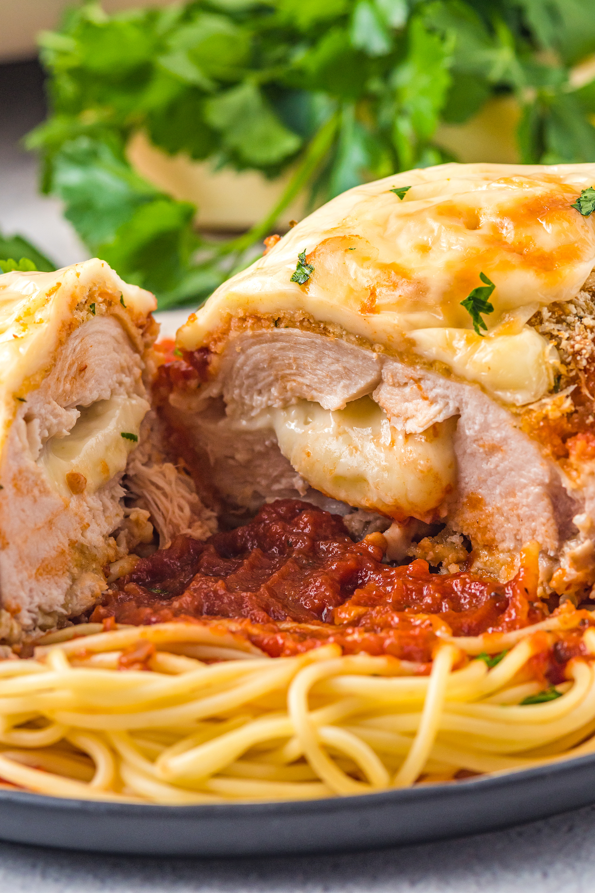Sliced chicken parmesan with melty cheese inside. 