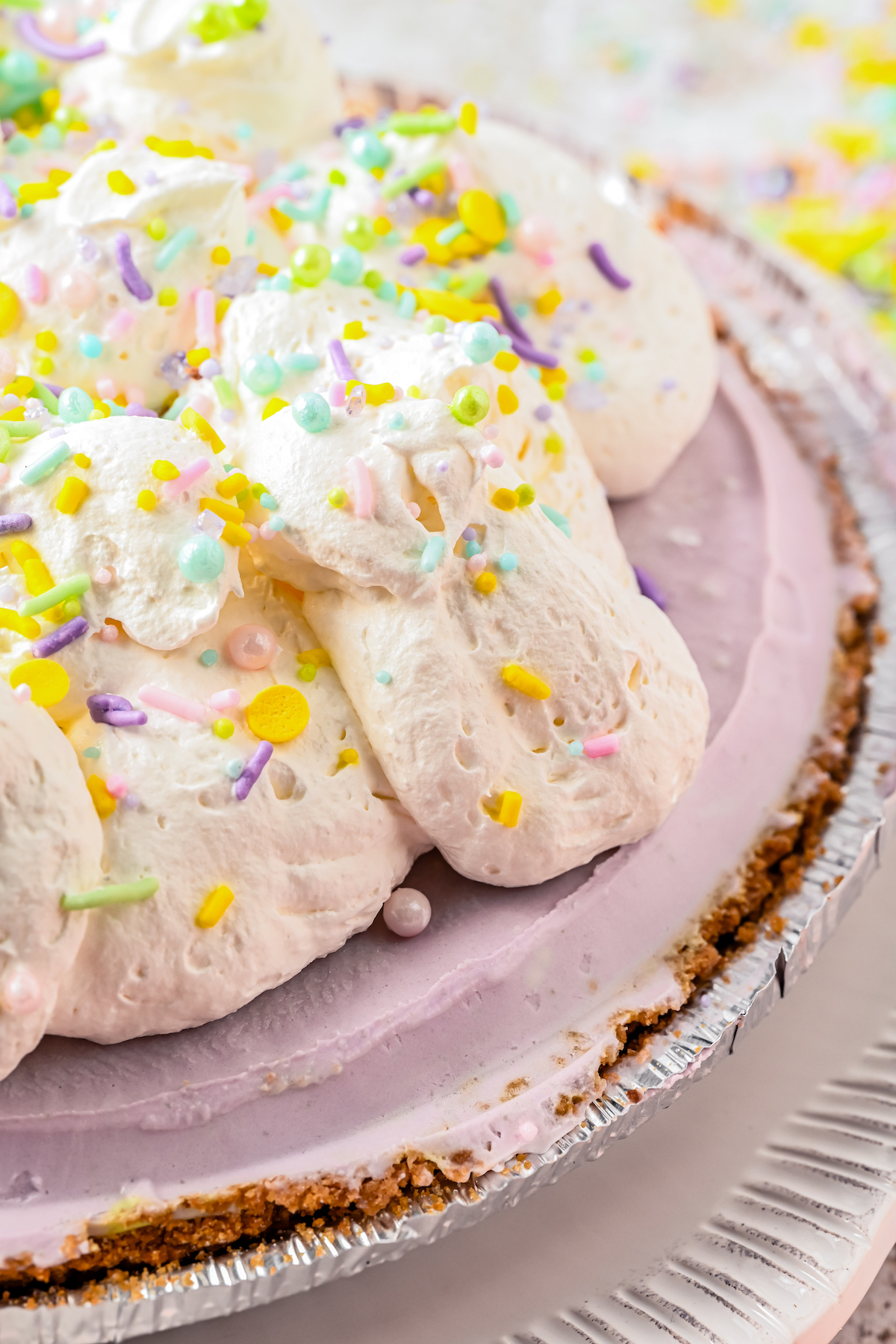 Close-up shot of a cheesecake with whipped topping and sprinkles.
