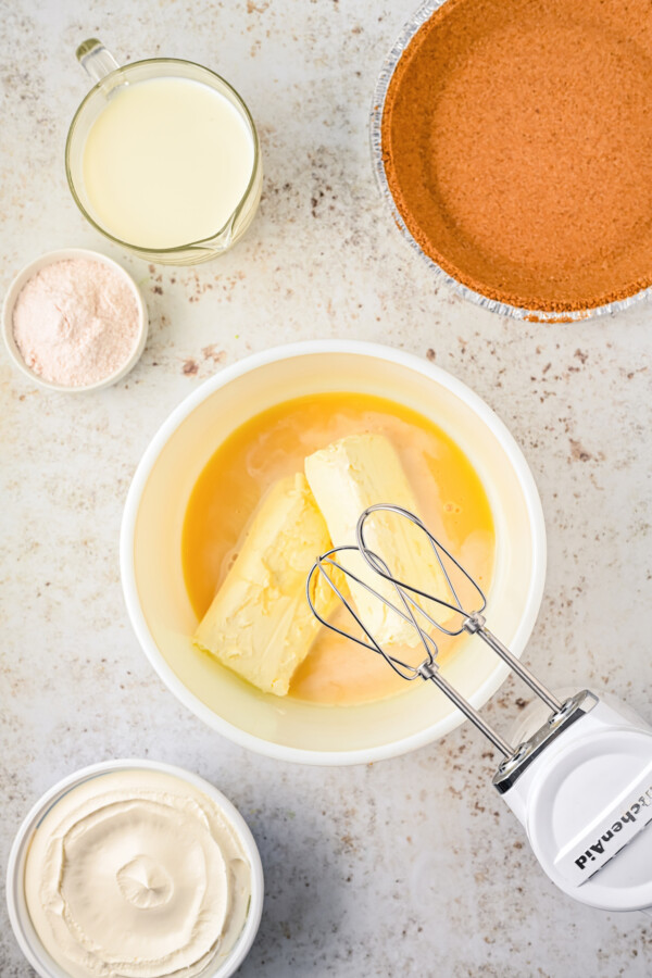Using a hand-mixer to beat cream cheese.