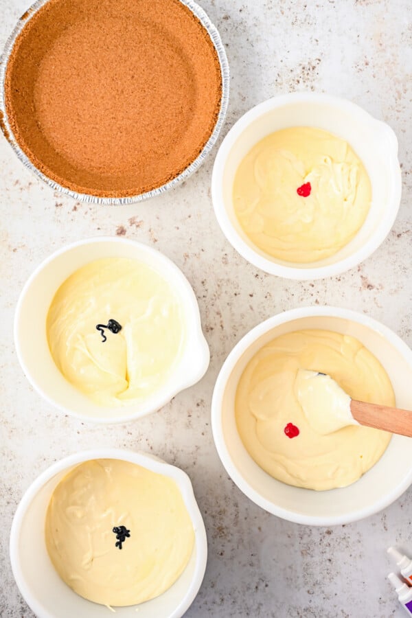 A pie crust and five bowls of cream cheese filling.