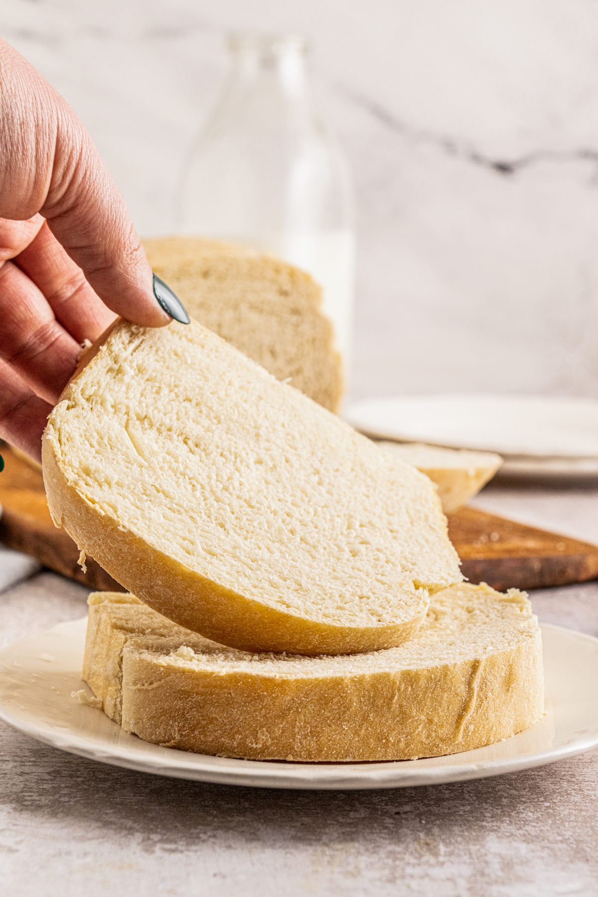 Lifting a slice of potato bread to show the softness of the slice.