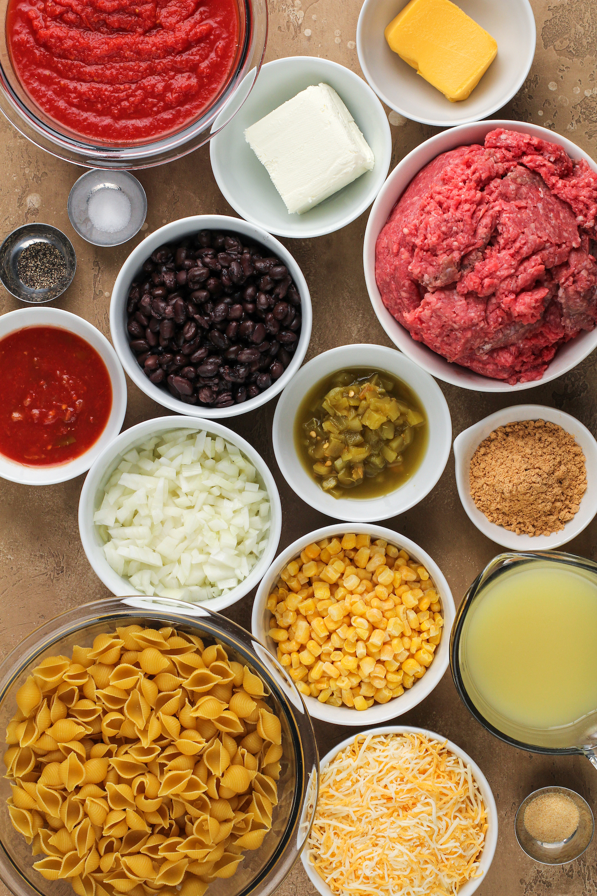 Taco pasta ingredients measured and arranged in dishes on a work surface.