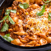 A slow cooker insert filled with pasta and sauce.