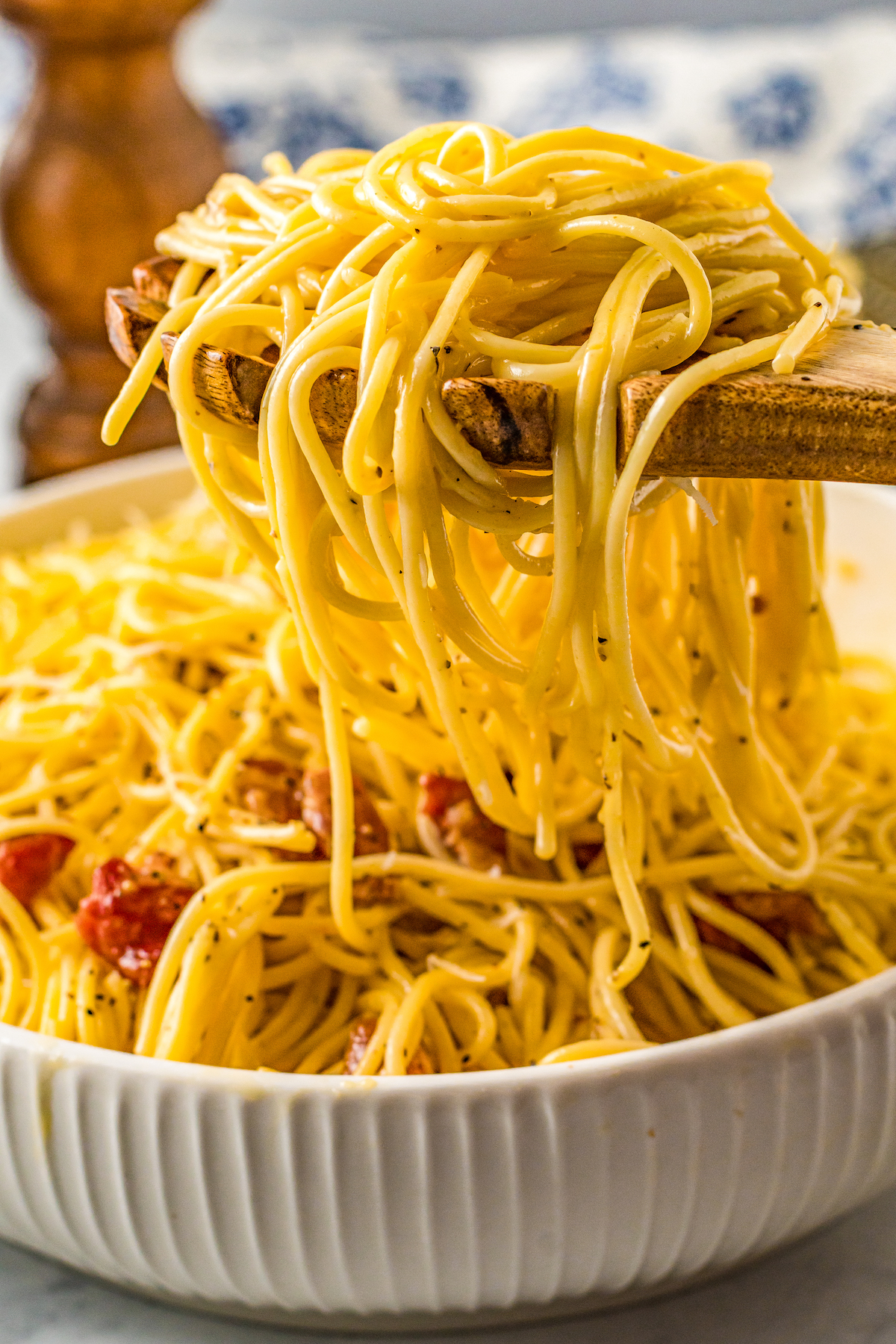 Picking up spaghetti carbonara with a wooden spoon.